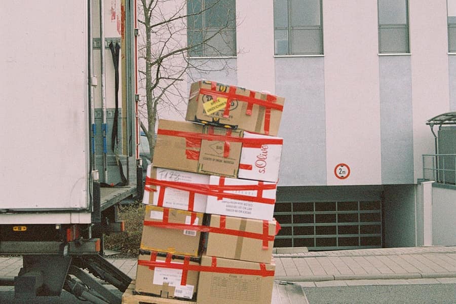Camión de caja con plataforma elevadora descargando un palé de cajas en un edificio comercial